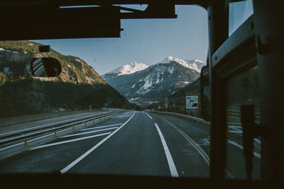 Road leading towards mountains seen through car windshield