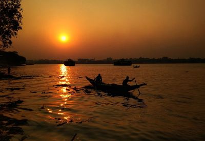 Silhouette boat in sea against sky during sunset