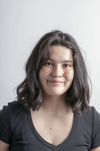 Portrait of smiling teenage girl sitting against white background