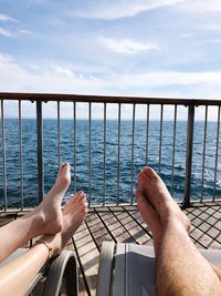 Low section of man relaxing on sea against sky