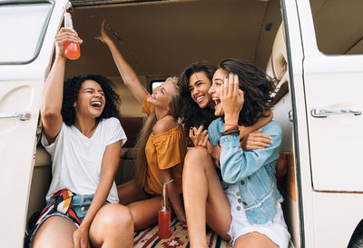 Happy friends sitting in car