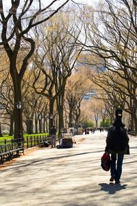 Rear view of man walking on footpath in city