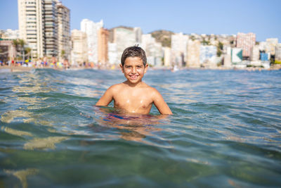 Funny kid into the water on an urban beach