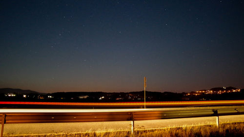 Light trails on landscape against sky at night