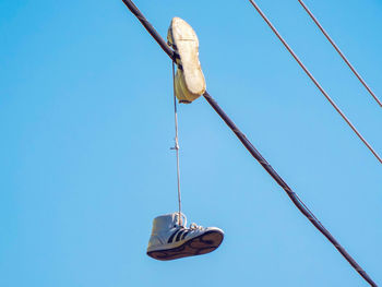 Low angle view of shoes against clear blue sky