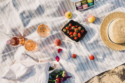 Rose wine, peaches and strawberries on the beach towel. beautiful summer picnic near the sea.