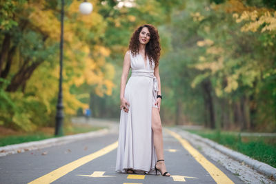 Woman standing on road against trees