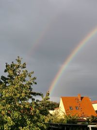 Low angle view of rainbow over buildings against sky
