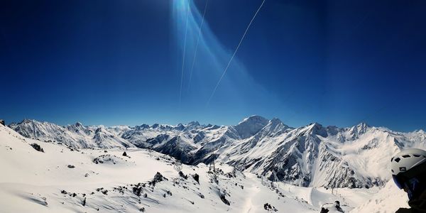Scenic view of snowcapped mountains against blue sky