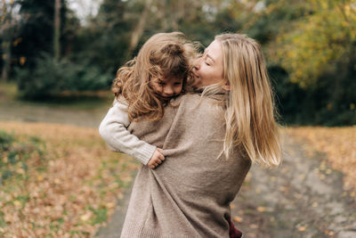 Happy young mother and little daughter are playing and fooling around outside.