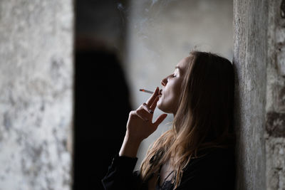 Side view of woman standing against wall