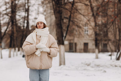 Portrait of young woman standing in forest during winter