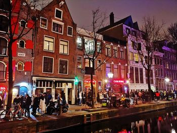 People on street against illuminated buildings in city at night