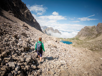 Woman hiking on rocky mountain during sunny day