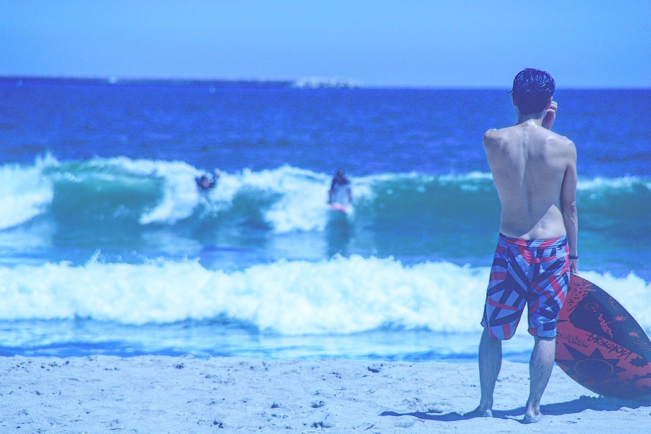 sea, horizon over water, standing, rear view, blue, leisure activity, beach, clear sky, men, lifestyles, vacations, water, beauty in nature, tourist, full length, scenics, togetherness, tranquil scene, casual clothing, nature, tranquility, wave, shore, getting away from it all, escapism, summer, tourism, remote, solitude