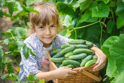 Portrait of girl with cucumbers in basket