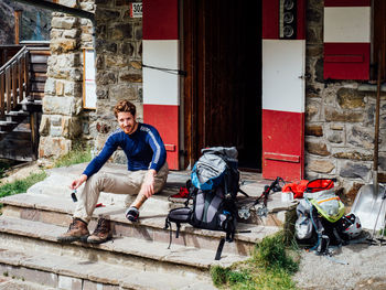 Young hiker sitting on steps at entrance of building