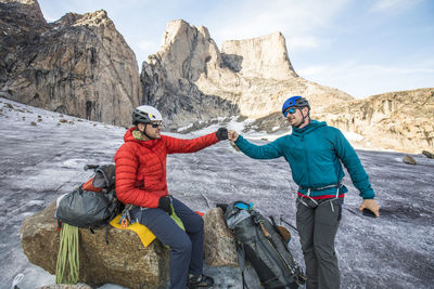 Two climbers fist bump below mountain after a successful climb