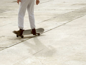 Low section of man skateboarding on footpath