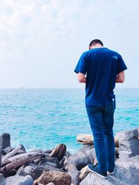 Rear view of man looking at sea against sky