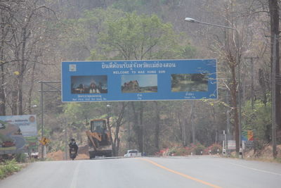 Information sign on road by trees