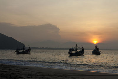 Silhouette boats in sea against sky during sunset