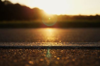 Surface level of road against sky during sunset