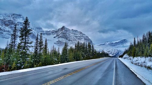 Road by snowcapped mountain against sky