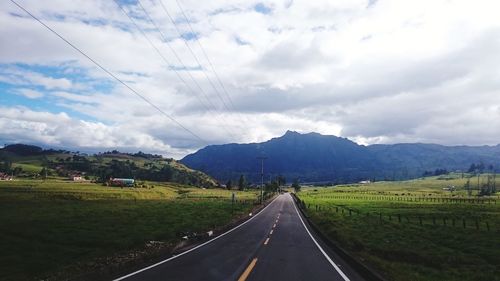 Road leading towards mountains against sky