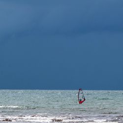 One lonely man surfing in sea against a dark sky