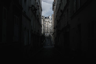 Walkway amidst buildings in city against sky