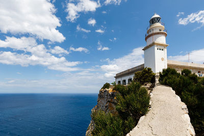 Lighthouse amidst sea and buildings against sky