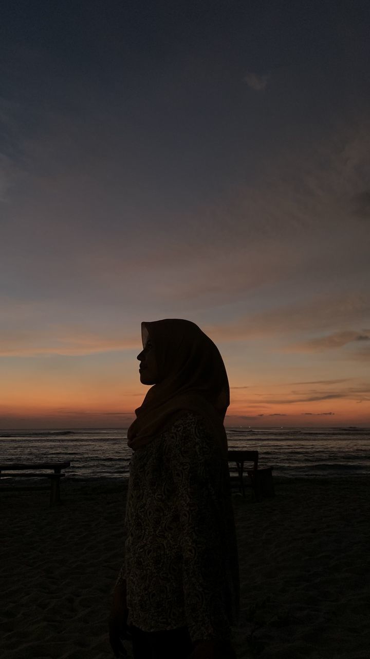 SILHOUETTE WOMAN STANDING ON BEACH DURING SUNSET