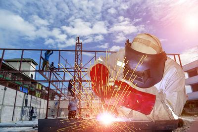 Man working on metal structure against sky