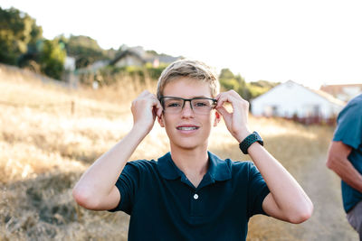 Portrait of a teen boy with braces trying on his dad's eyeglasses