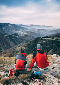 Rear view of people looking at mountains against sky