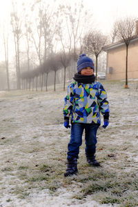 Full length of boy looking away while standing on field during winter