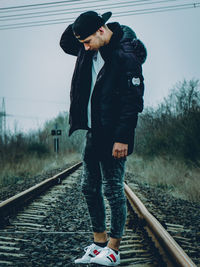 Man standing by railroad tracks against sky