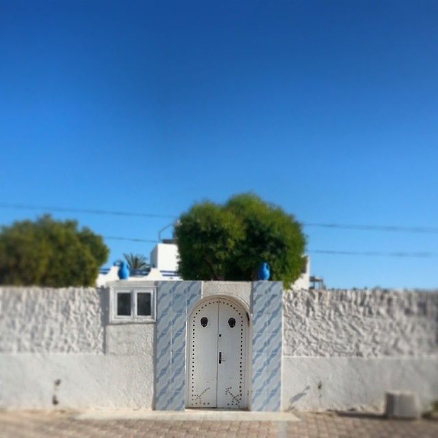 built structure, architecture, building exterior, blue, clear sky, copy space, house, tree, power line, low angle view, day, residential structure, outdoors, no people, cable, plant, sunlight, nature, residential building, sky