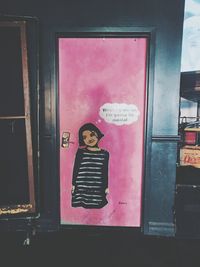 Full length of smiling young woman standing against door