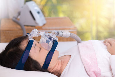 Close-up of woman with oxygen mask lying on bed at hospital