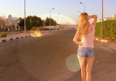 Rear view of woman standing on road in city