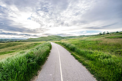 Road amidst field against sky