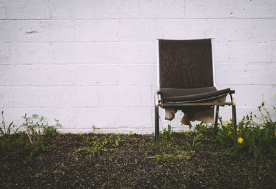 Abandoned chair against brick wall