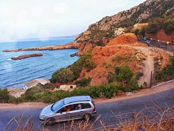 Car on road by sea against sky