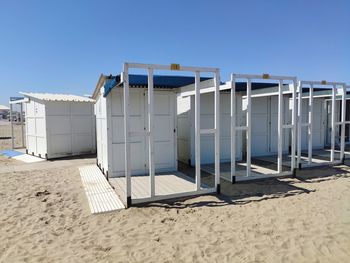 Hut on beach against clear blue sky