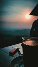 Close-up of coffee on sea against sunset sky