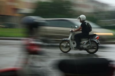 Blurred motion of young man riding motorcycle on city street