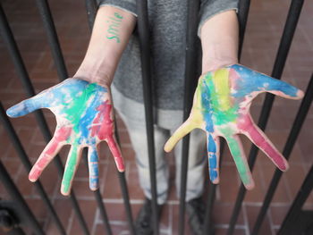 High angle view of person with colorful hands standing by gate