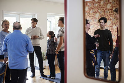 Multi-ethnic friends and family talking while having drink at social gathering